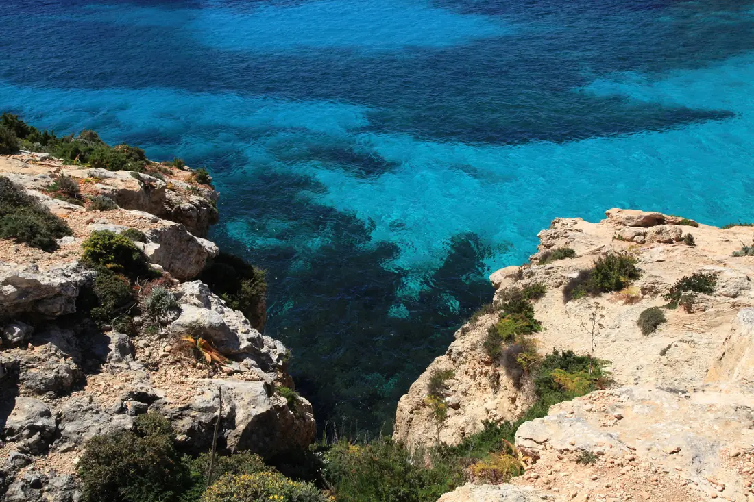 Clear turquoise water below the limestone cliffs of Comino