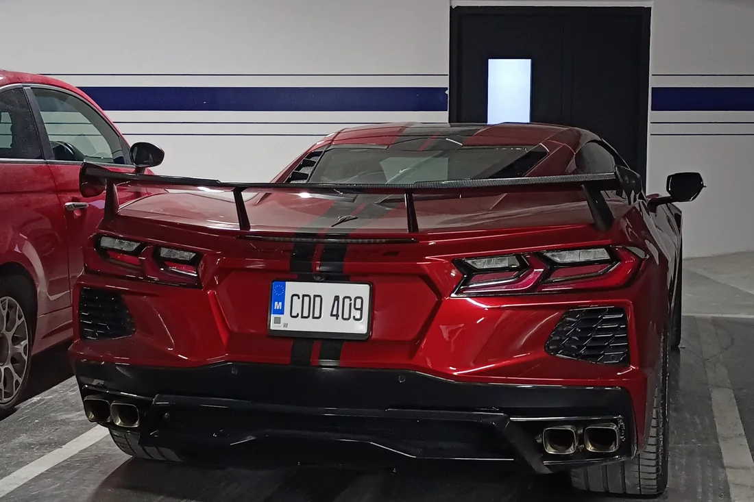 A red Corvette C8 parked in a clean underground parking garage in Malta