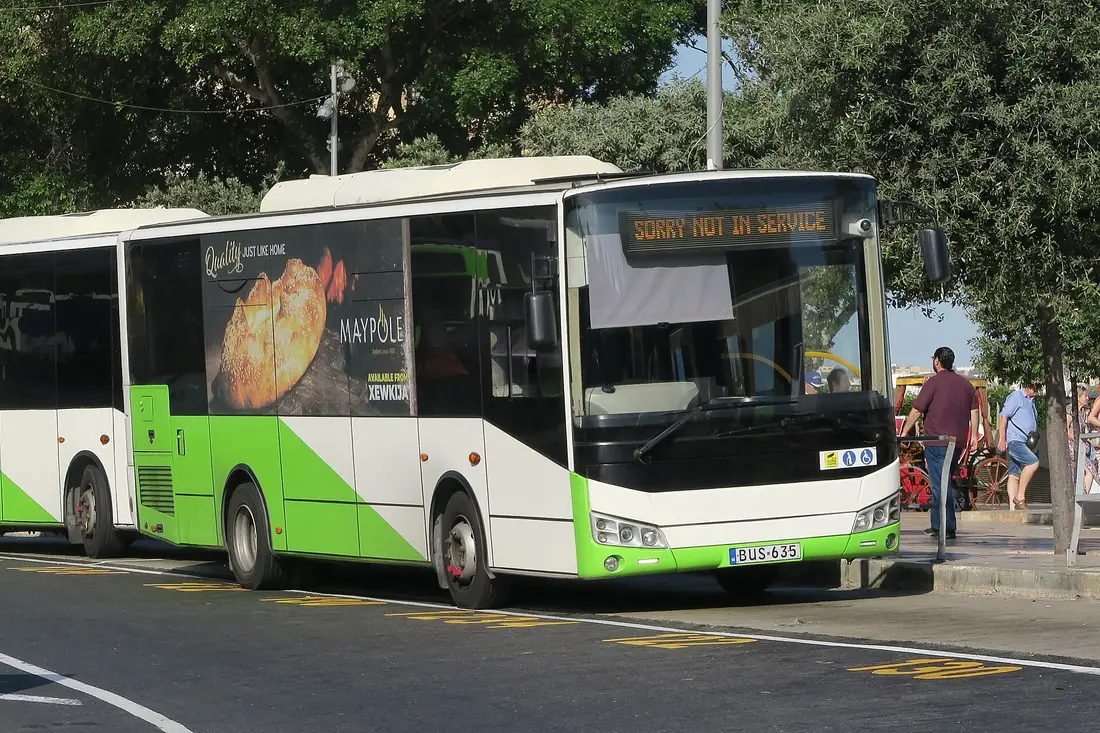 A green and white Malta Public Transport bus at a stop, showing Sorry Not In Service