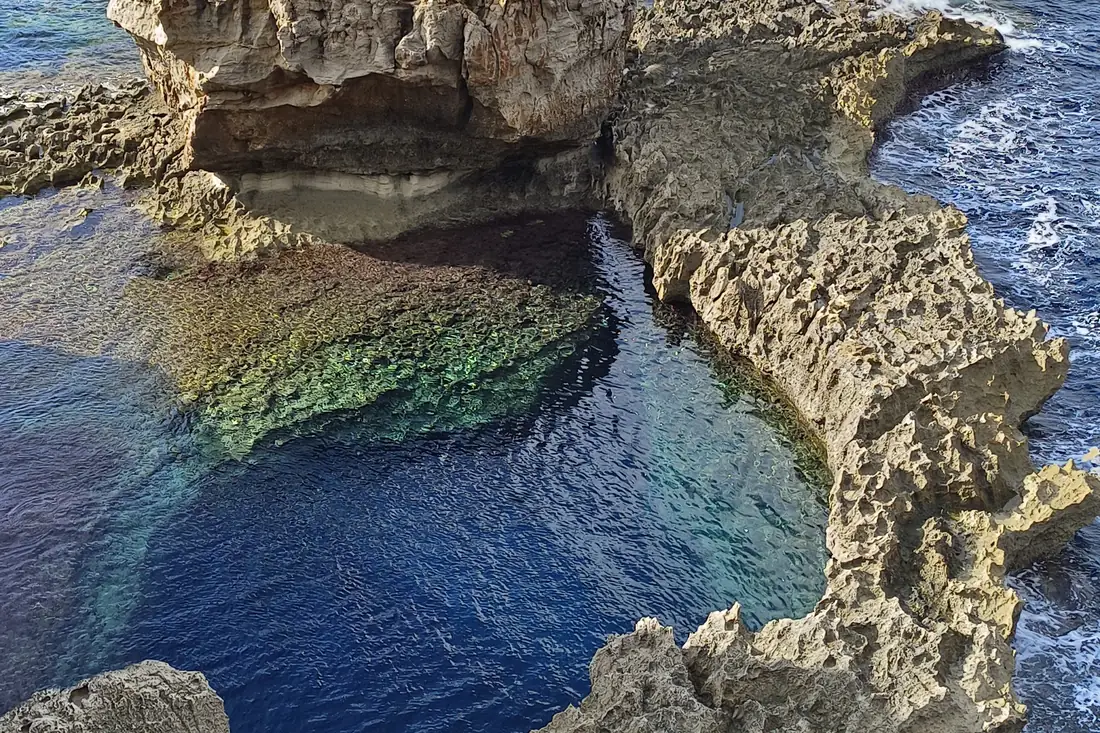 A natural rock pool on the Maltese coast with the open sea behind